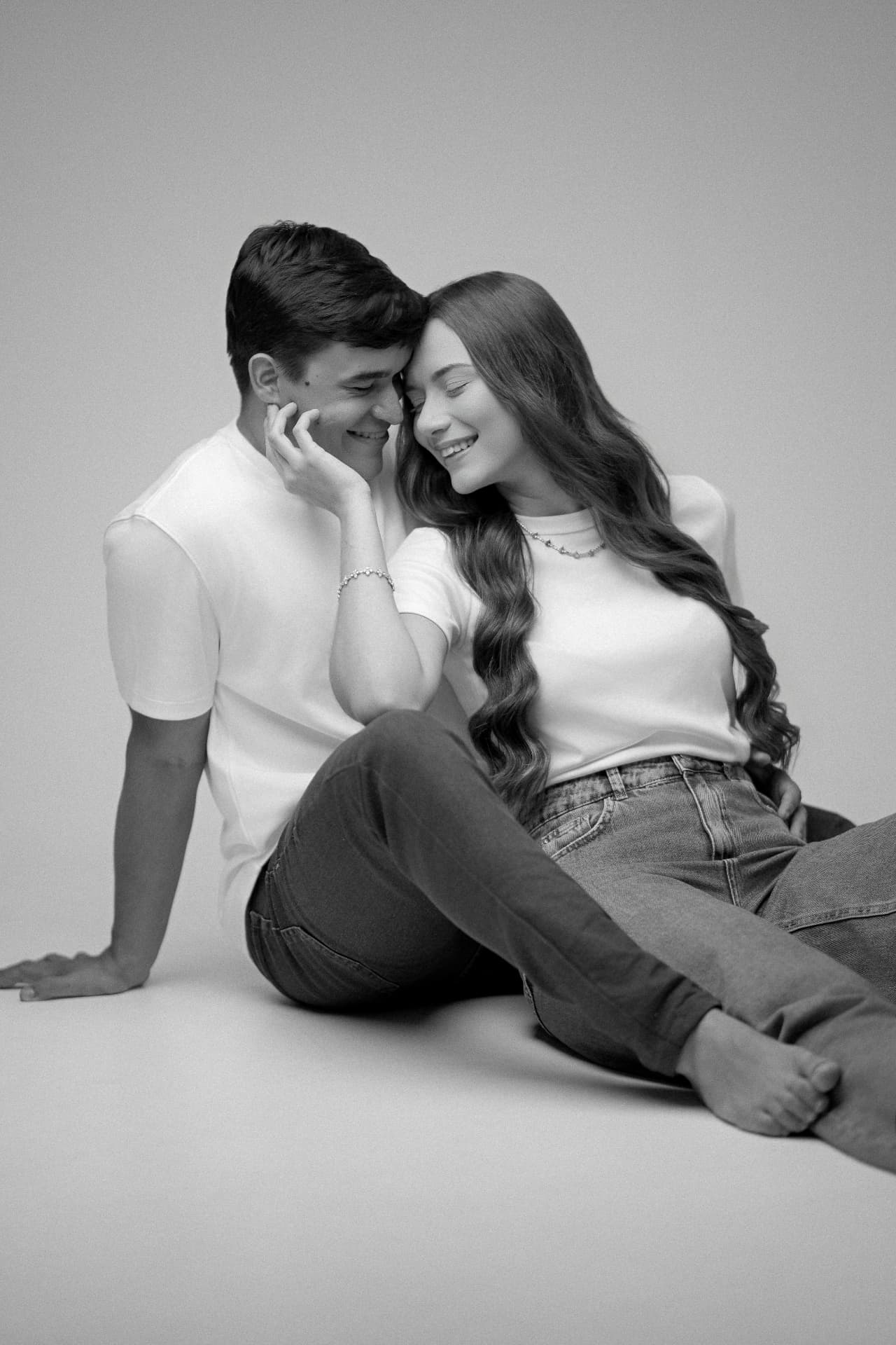 Aryanne e Sávio sentados e sorrindo no estúdio